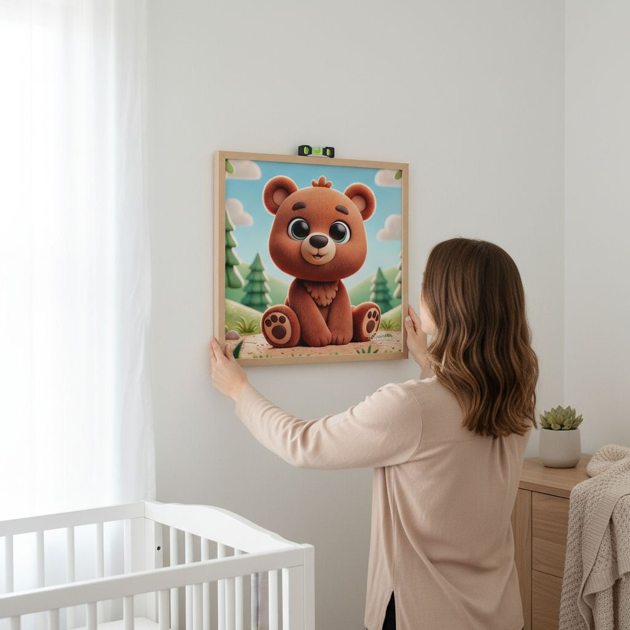 A woman is hanging a framed picture of a cartoon bear on a wall in a nursery.