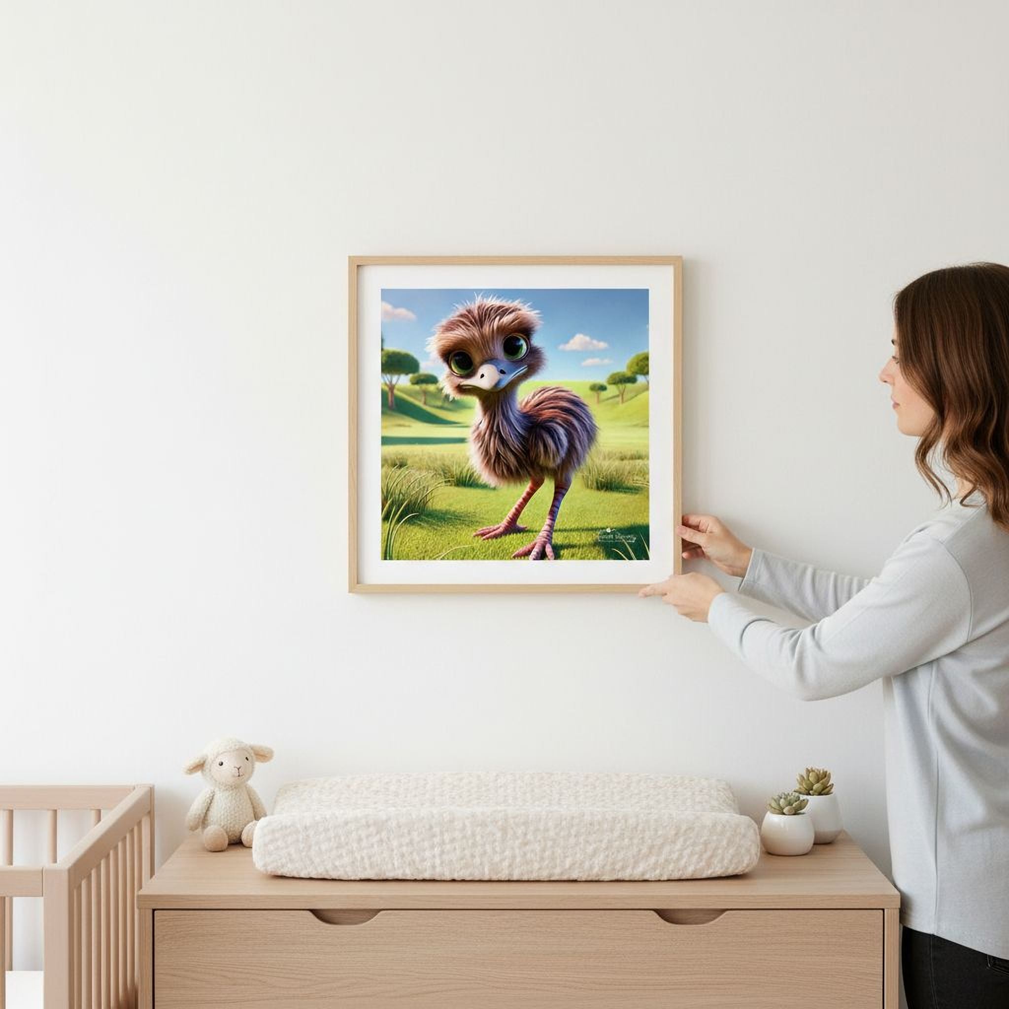 A woman hangs a framed picture of a colorful cartoon bird on a wall in a room with a changing table, a stuffed animal, and other decor.