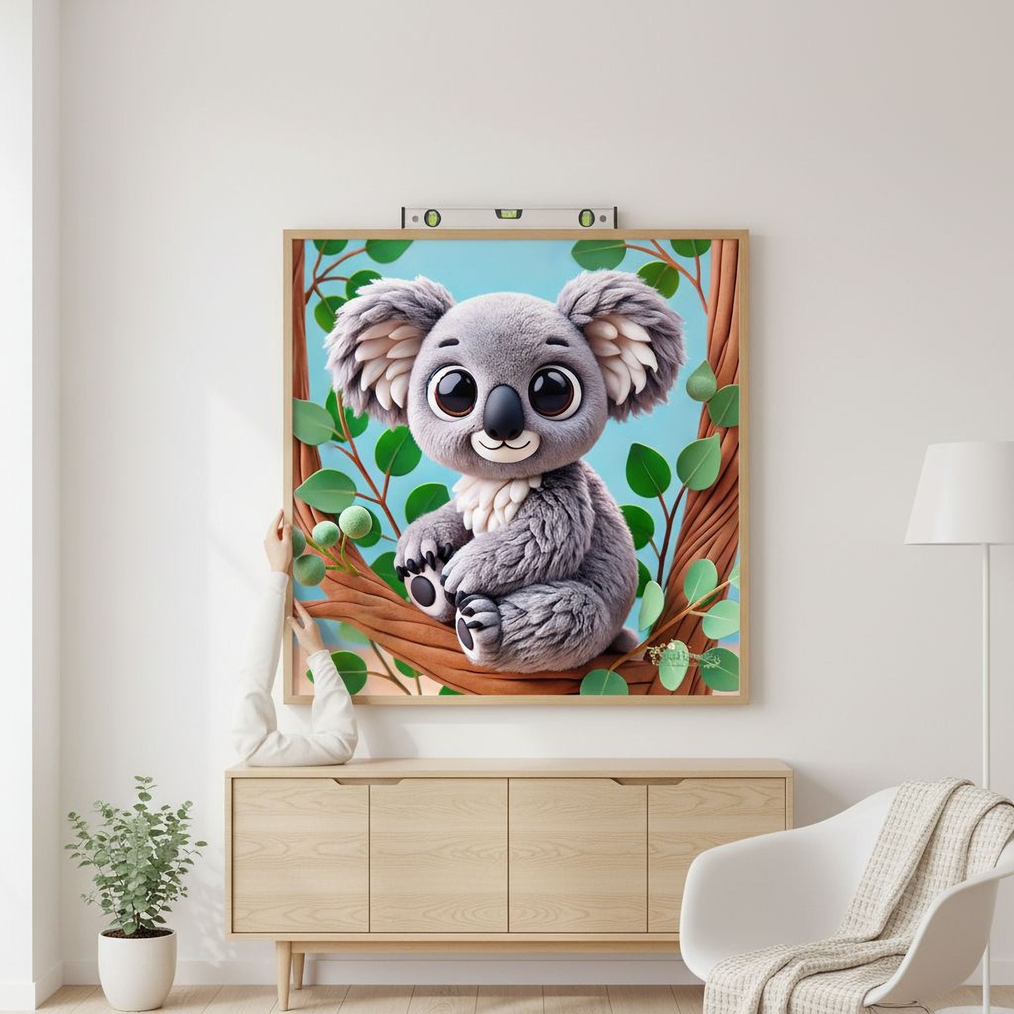 a framed illustration of a koala bear sitting on a tree branch, surrounded by green leaves.